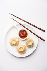 Dumpling momos food from Nepal or Ladakh served with red chilli chutney over moody background. Selective focus