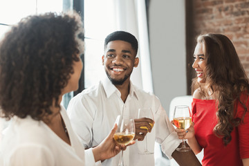 Multiracial people talking and drinking wine at home party