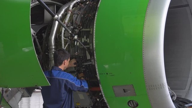 Engine and chassis of the passenger airplane under heavy maintenance. Engineer checks the aircraft engine. 4k