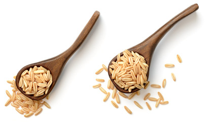 uncooked oats in the wooden spoon, isolated on white, top view