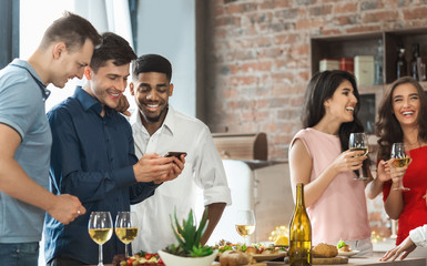 Male friends using smartphone while partying at home