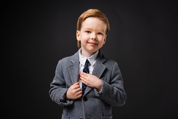 adorable smiling boy in suit isolated on grey