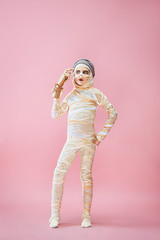 Studio image of a young teen girl bandaged, on pink background. Bloody Halloween theme: the crazy maniak studio background