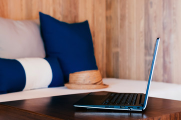 Vacation working, Laptop computer on wood table in living room with couch and pillows