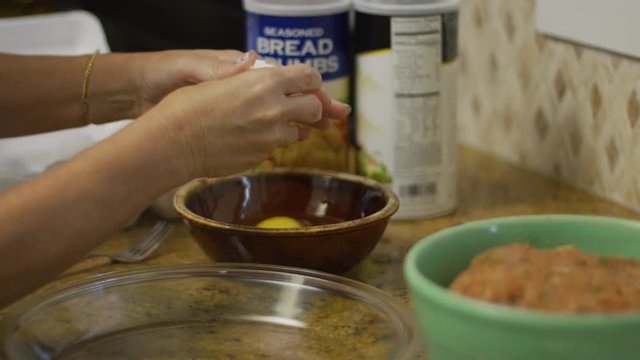 Woman cracking an egg with deviled crab meat in the foreground