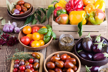 Colorful vegetables on rural wooden table, bell peppers, eggplants and tomatoes