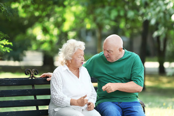 Fototapeta premium Elderly couple resting on bench in park