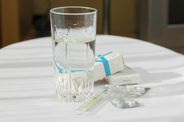 Таблетки с термометром и стаканом воды.