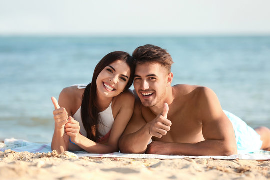 Happy young couple lying together on beach