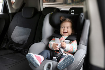 Cute child sitting in safety chair inside car