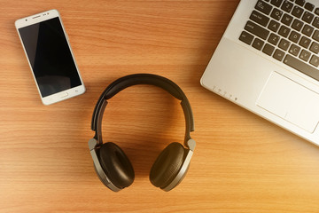 Over-Ear Headphone and smart phone with laptop on wooden floor,used electronics gadgets, Top view