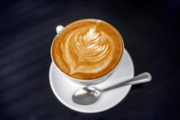 coffee cappuccino in cup with froth of milk on black table