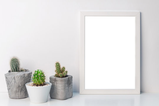 White empty mockup frame with cacti in concrete pots on the shelf