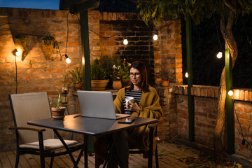 Woman browsing news in her backyard. night scene.