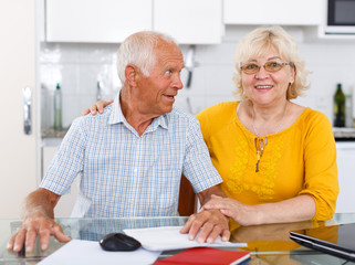 Happy mature couple with documents sitting at table in home