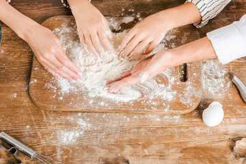Fototapeta premium cropped shot of child and women making dough together on wooden board