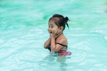 Happy baby Asian girl in swimming pool