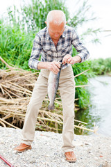 Fototapeta premium Fisherman pulling fish from river
