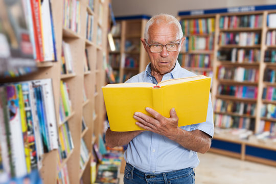 Older man reader with interest looking inside of book
