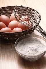 Fototapeta na wymiar Eggs, Flour And Scutcher On Wooden Table Close-up