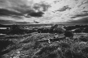 Man sitting on the bench watching the sunset, black and white, England UK