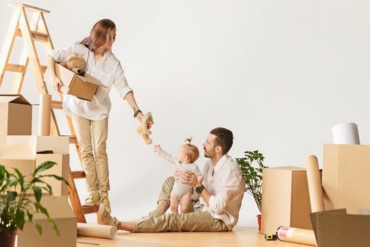 Couple moving to a new home. Happy married people with newborn child buy a new apartment to start life together. The family at repair and relocation planing to accommodation against boxes