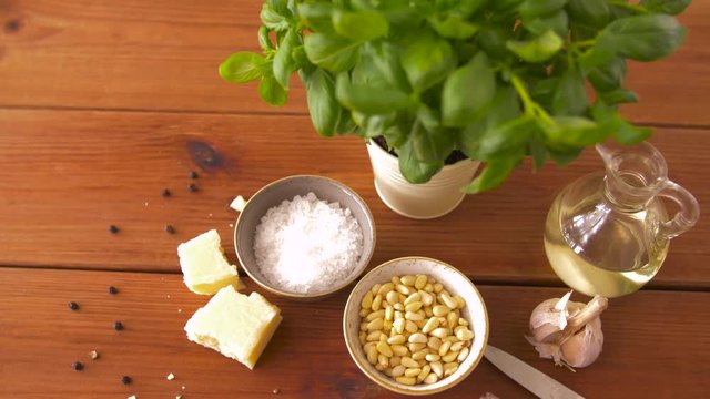 food and culinary concept - parmesan cheese, pine nuts, sea salt and garlic for basil pesto sauce making on wooden table