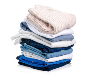 Stack of clothing jeans sweaters on a white background isolation