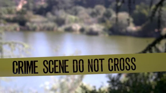 CRIME SCENE TAPE OVERLOOKING A LAKE,  4K SLIDER SHOT