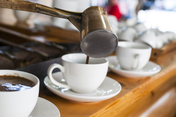 three cups of coffee, man pours coffee from cezve, concrete background