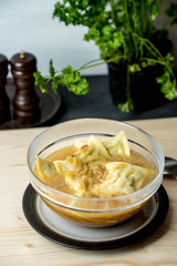maultaschen, German, traditional dumplings in a bowl with onion soup, next to fresh parsley, salt shaker and pepper pot