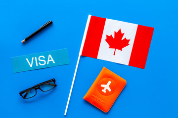 Visa to Canada concept. Text visa near passport cover and canadian flag on blue background top view