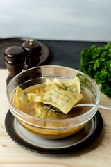maultaschen, German, traditional dumplings in a bowl with onion soup, next to fresh parsley, salt shaker and pepper pot