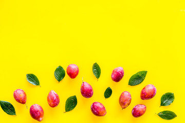 Summer harvest of red plum.  Red plum and leaves pattern on yellow background top view space for text