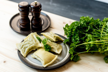 maultaschen, German, traditional dumplings on a plate, next to fresh parsley, salt shaker and pepper pot