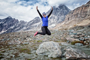 Woman jumping from a rock in the Italian mountainous alps