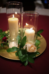 Obraz na płótnie Canvas Wedding Centerpiece Candles Surrounded by Greenery on a Gold Charger Plate