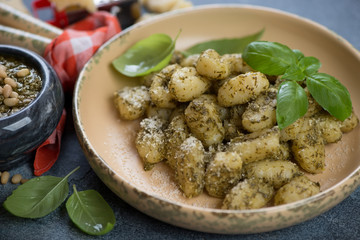 Close-up of potato gnocchi with green basil pesto in a serving pan, selective focus, studio shot