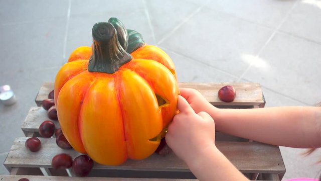 Two little girls playing feeding chestnuts to halloween pumpkin, child play, holiday decoration, faces unrecognizable, one takes pumpkin and the other cries at the end