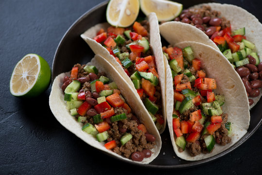 Close-up of tacos with minced beef meat, red beans and fresh vegetables filling, horizontal shot