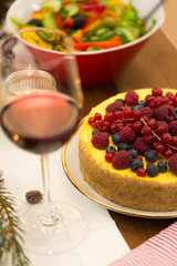 christmas dinner and eating concept - close up of berry cake and other food on table at home