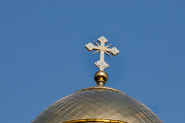 Fototapeta na wymiar The golden dome and the cross of the Orthodox church against the blue sky and clouds.