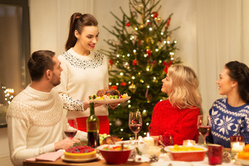 holidays and celebration concept - happy friends having christmas dinner at home