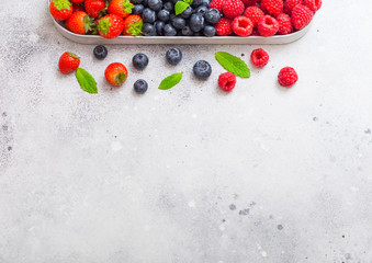 Fresh raw organic berries in in stainless steel tray on kitchen table background. Space for text. Top view. Strawberry, Raspberry, Blueberry and Mint leaf