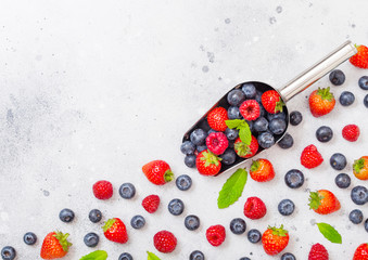 Fresh raw organic berries in steel scoop spoon on kitchen table background.Top view. Strawberry, Raspberry, Blueberry and Mint leaf