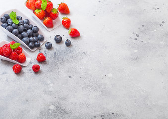 Fresh raw organic berries in white scoop spoon on kitchen table background. Space for text. Top view. Strawberry, Raspberry, Blueberry and Mint leaf
