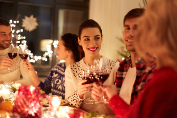 winter holidays and people concept - happy friends celebrating christmas at home feast and drinking...