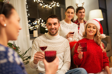 celebration and holidays concept - happy friends with glasses celebrating christmas at home party and drinking red wine