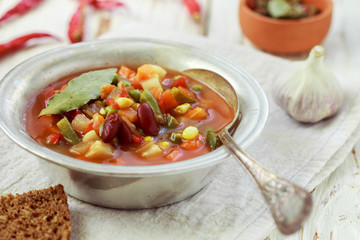Eintopf - German traditional thick soup with meat and vegetables - potatoes, carrots, onions, red and green beans, corn and tomatoes with seasonings and spices. Rustic style
