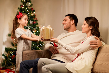 holidays, family and celebration concept - happy mother, father and little daughter with christmas present at home